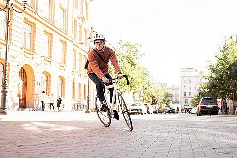 Ein Radfahrer mit Helm geht mit einer Aktentasche zur Arbeit