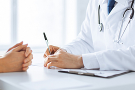 Arzt macht sich Notizen währen eines Patientengesprächs