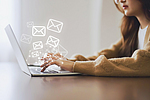 Frau nutzt Laptop und versendet Online-Nachrichten mit E-Mail-Symbol