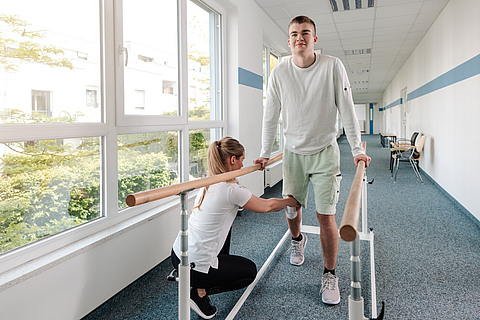 Therapeutin hilft jungem Mann in Reha