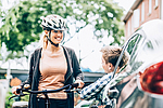 Eine Fahrradfahrerin unterhält sich mit einem Autofahrer durch das offene Fenster auf einer Straße.