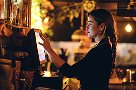 Servicekraft im Restaurant gibt Bestellung am Computer ein.